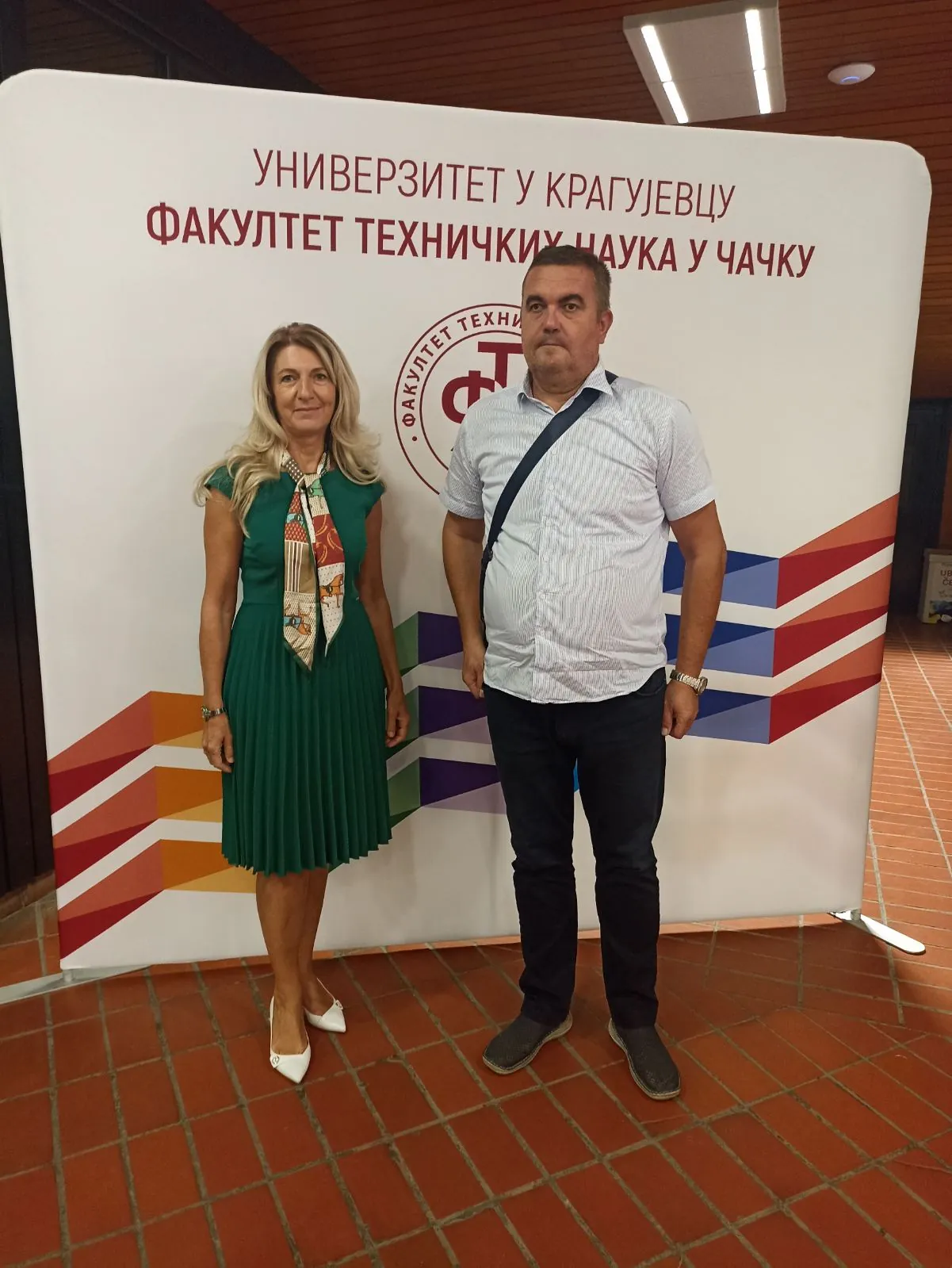 Danijela Milošević and Slobodan Lubura in front of the Faculty of Technical Sciences sign in Čačak.